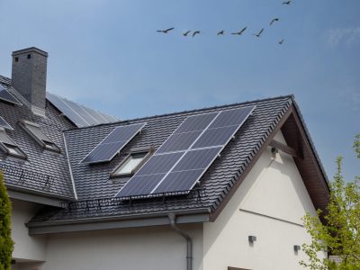 Solar Panel on a dark gable roof - blue sky and sun. Moder house, vertical shot.