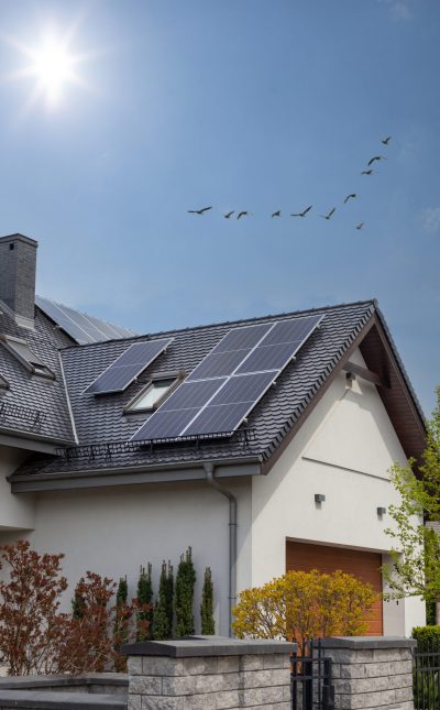 Solar Panel on a dark gable roof - blue sky and sun. Moder house, vertical shot.